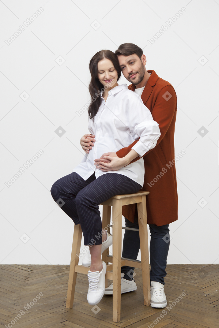 男人从后面可爱地拥抱坐着的孕妇