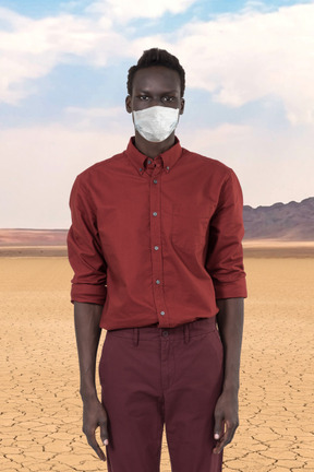 A man standing in a desert wearing a mask