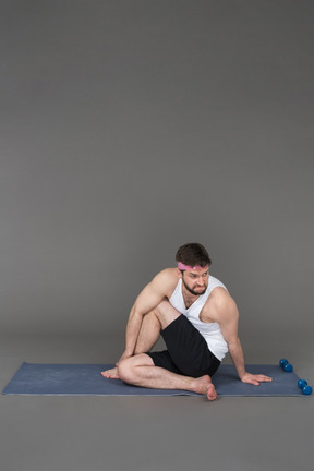 Sporty guy stretching after the workout