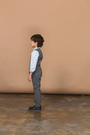 Side view of a cute boy in grey suit