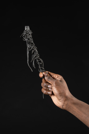 Close-up of a human hand holding black pasta