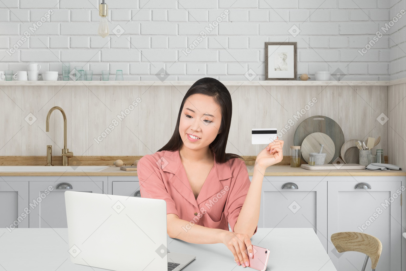 A woman sitting at a table with a laptop and a credit card