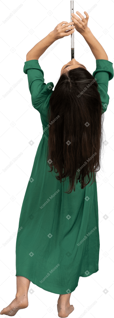 Вид сзади молодой леди в зеленом платье, играющей на флейте, откинувшись назад