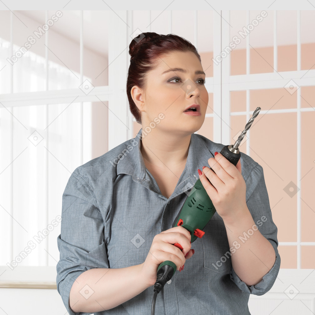 A woman holding a drill in a room