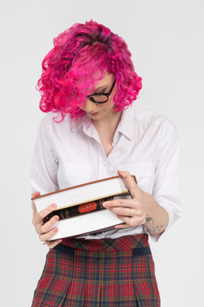 책과 함께 포즈를 취하는 분홍색 머리 십 대 소녀