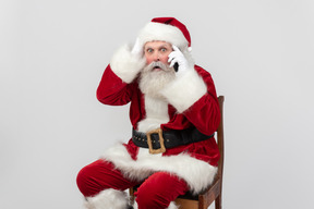 Weihnachtsmann am telefon sprechen und ziemlich überrascht aussehen