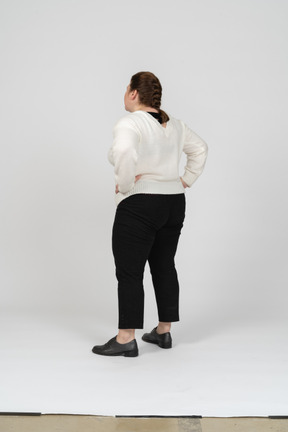 Retrovisor de uma mulher gorducha em roupas casuais em pé com as mãos na cintura