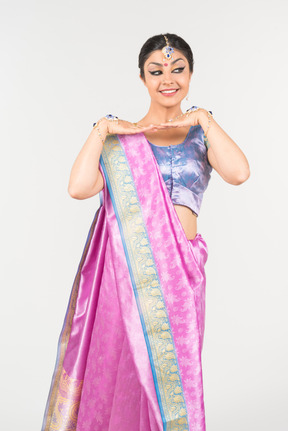 Young indian woman in purple sari standing in dance position