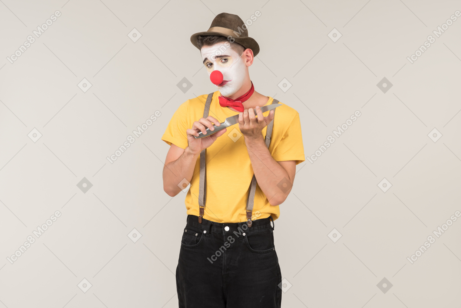 Male clown using knife as nail file