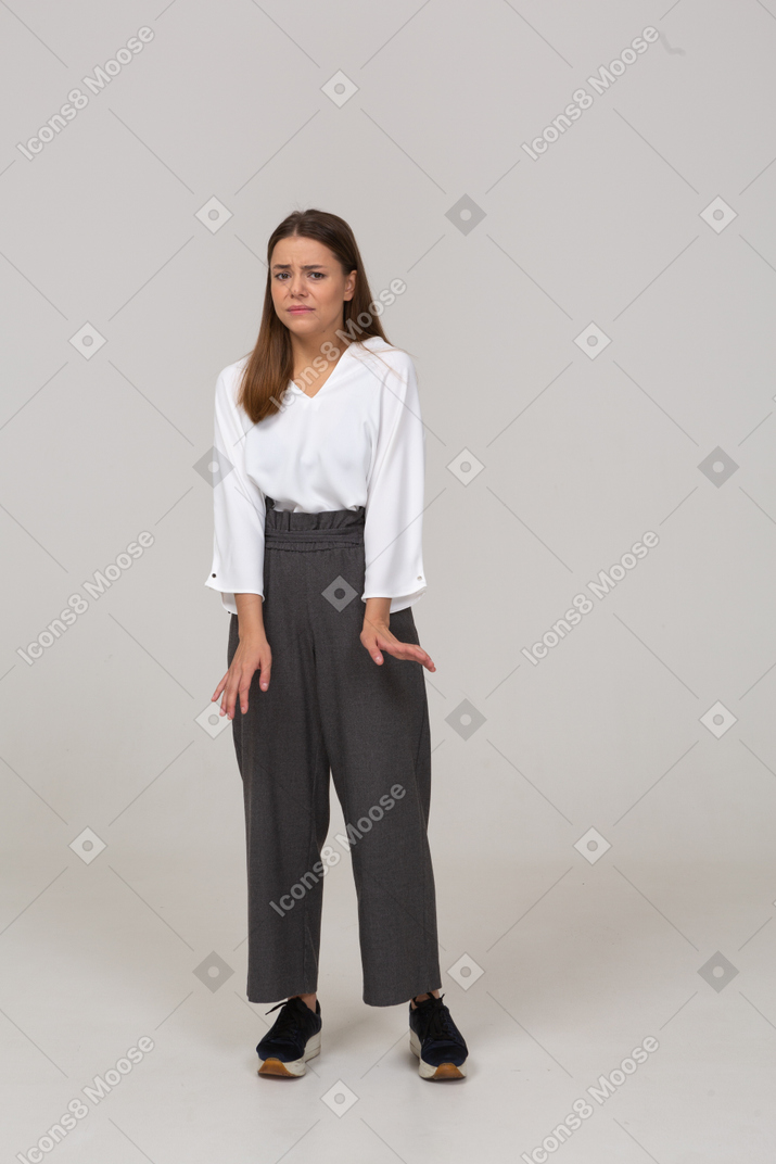 Vue de face d'une jeune femme en vêtements de bureau regardant la caméra