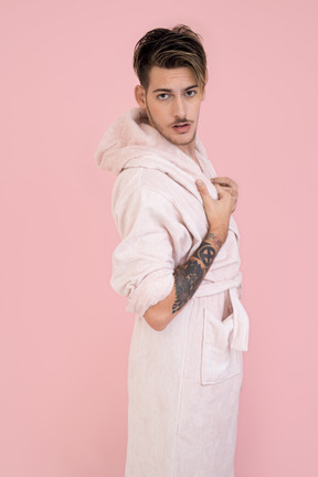 Beau mec en robe rose debout avec ses mains dans les poches