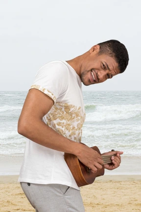 A man playing a ukulele on the beach