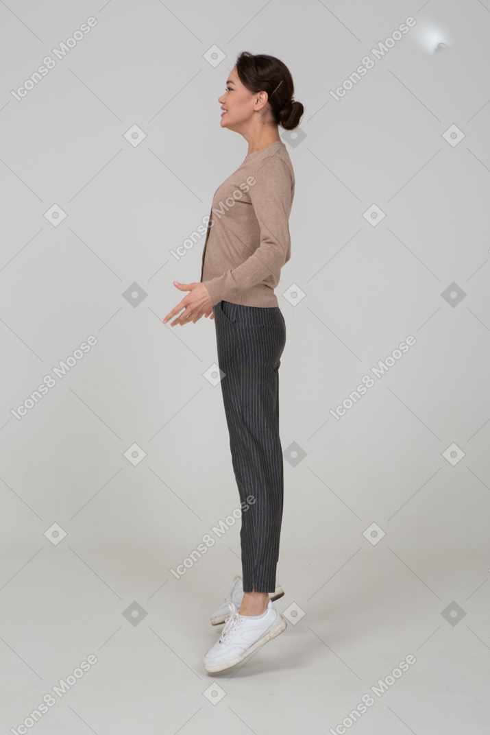 Side view of a smiling jumping lady in beige pullover
