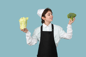 Kid boy chef holding chinese cabbage and broccoli