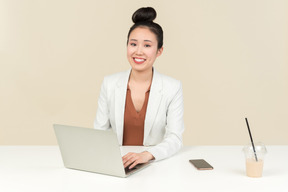 Smiling asian female office worker working on laptop