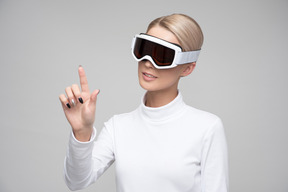 Young blonde woman in ski goggles using invisible digital interface