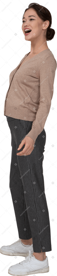 Vue de trois quarts d'une femme en riant en pull et pantalon mettant la main sur la hanche