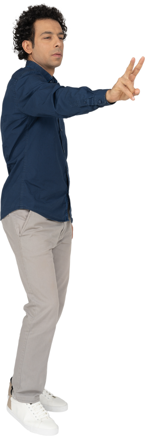 Vista frontal de um homem com roupas casuais mostrando o sinal v