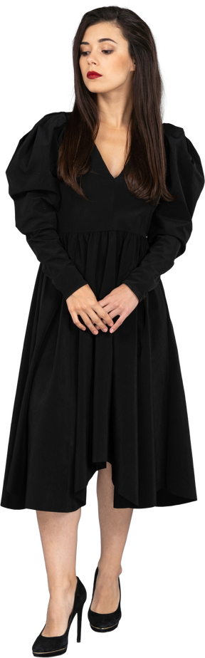Vue de face d'une jeune femme vêtue d'une robe noire, main dans la main