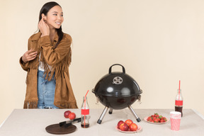 Young asian woman standing near closed grill on the table