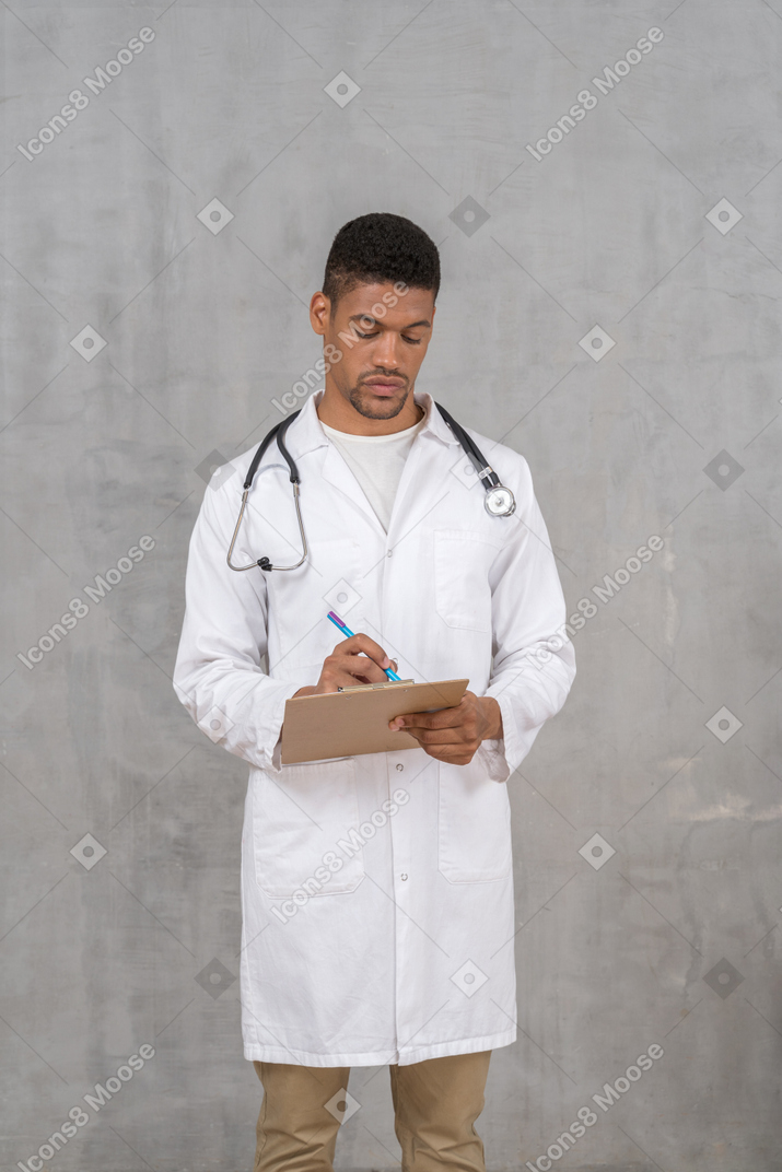 Vista frontale del giovane medico maschio che prende appunti