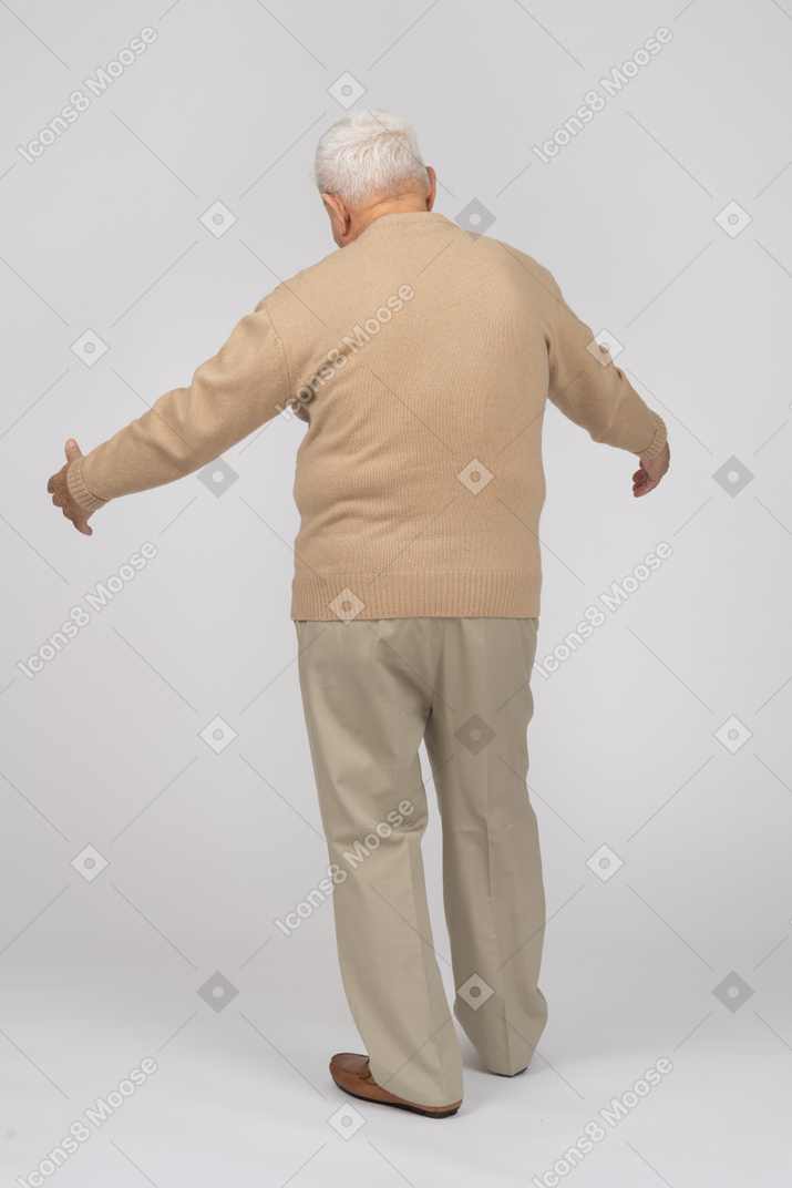 Rückansicht eines alten mannes in freizeitkleidung, der mit ausgestreckten armen steht