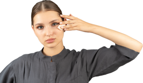 Молодая женщина в комбинезоне снимает макияж, вид спереди