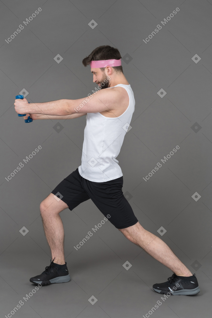 Homem estendendo os braços com halteres de perfil