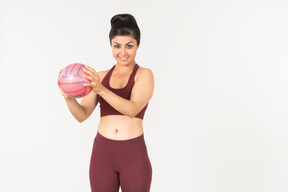 Smiling young indian woman holding pink ball