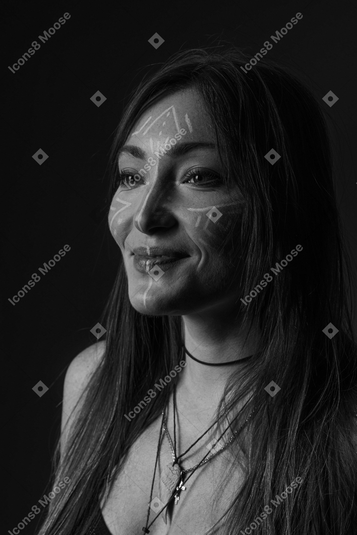 Side view noir picture of a young female with face art looking aside and smiling