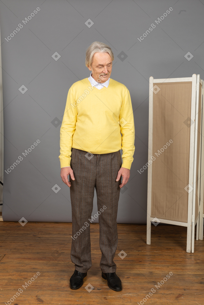 Front view of a smiling old shy man looking down