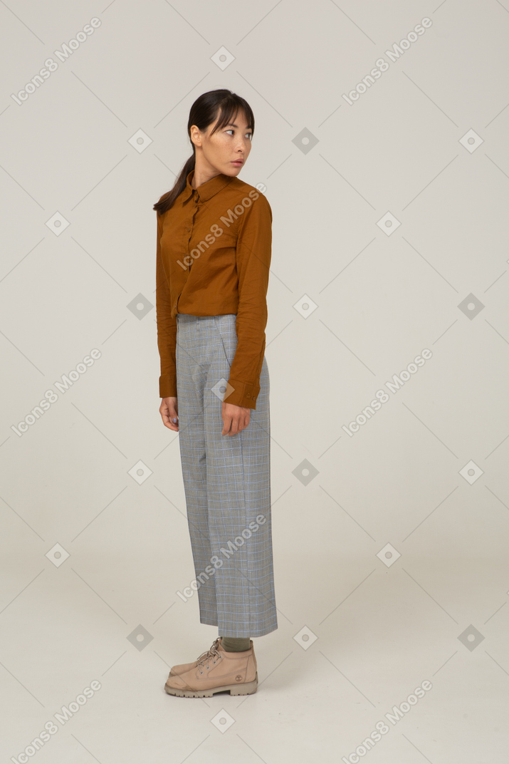 Vista laterale di una giovane donna asiatica in calzoni e camicetta che si allontana