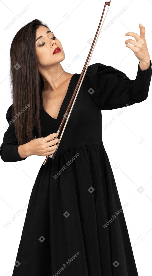 Vista frontal de uma jovem de vestido preto impressionando ao tocar violino