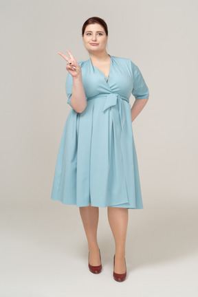 Front view of a woman in blue dress showin v sign