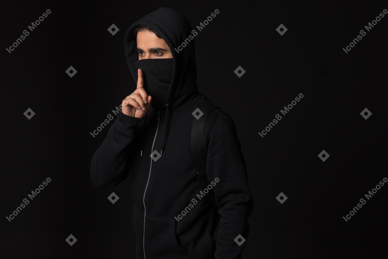 Хакер парень стоит в темноте и показывает жест молчания