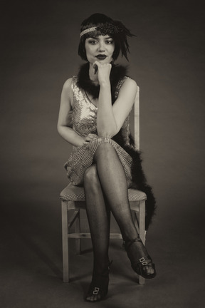 Retrato en blanco y negro de un flapper americano vintage sentado pierna a pierna