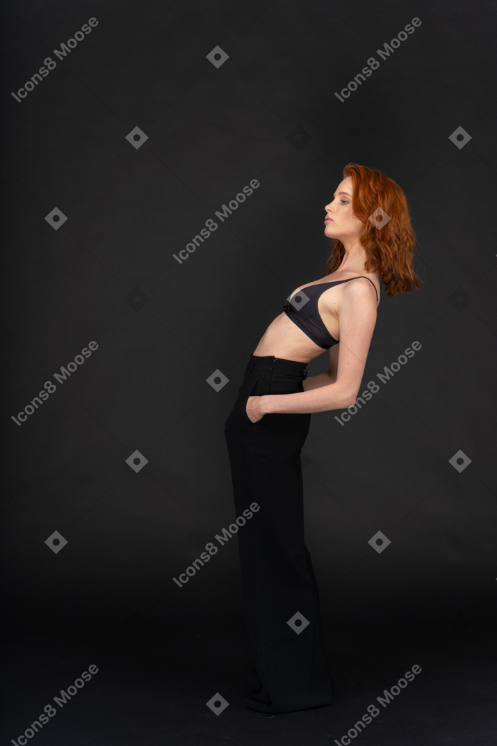 A side view of the young beautiful girl posing on the black background