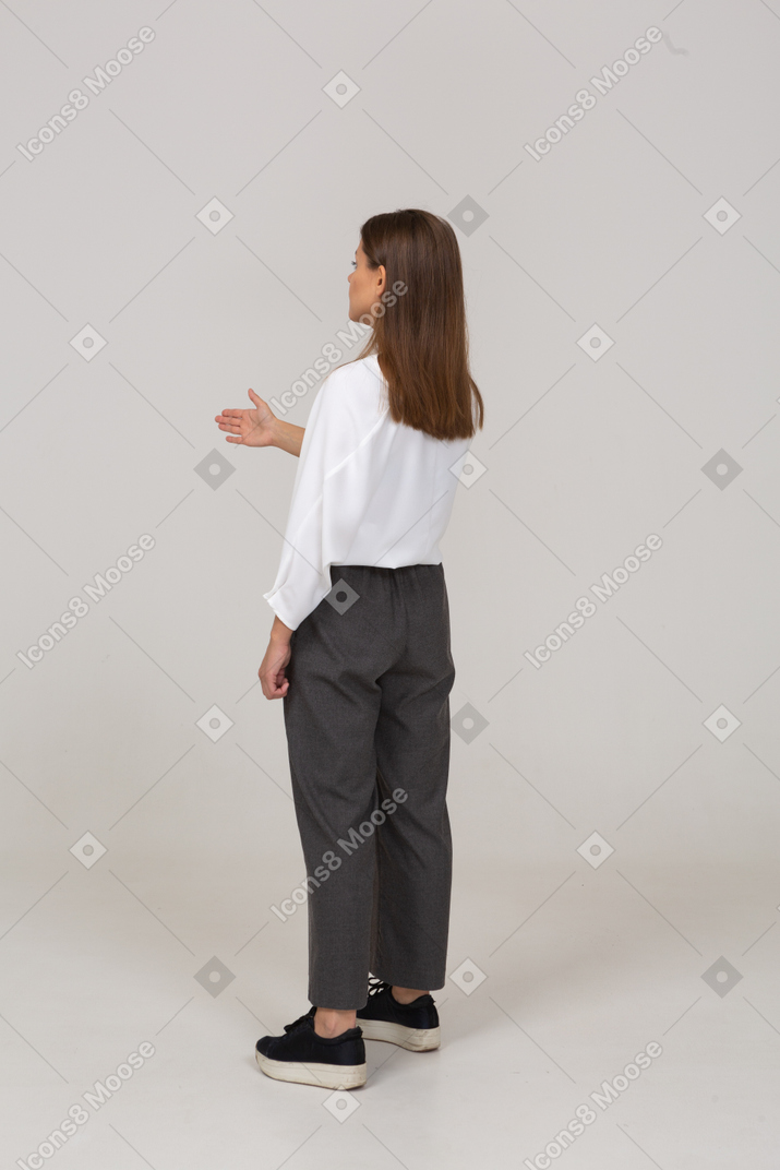 Three-quarter back view of a young lady in office clothing showing the right direction