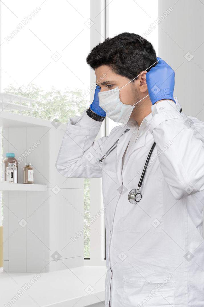 A male doctor putting on a face mask