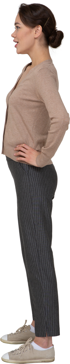 Vista laterale di una giovane donna in pullover beige mettendo le mani sui fianchi