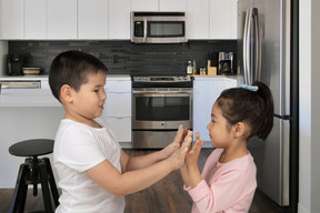 Um menino e uma menina tocando conchas na cozinha