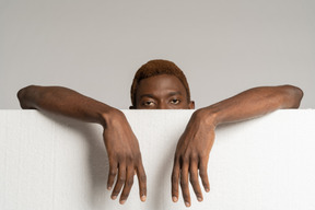 Front view of a young afro man standing behind styrofoam