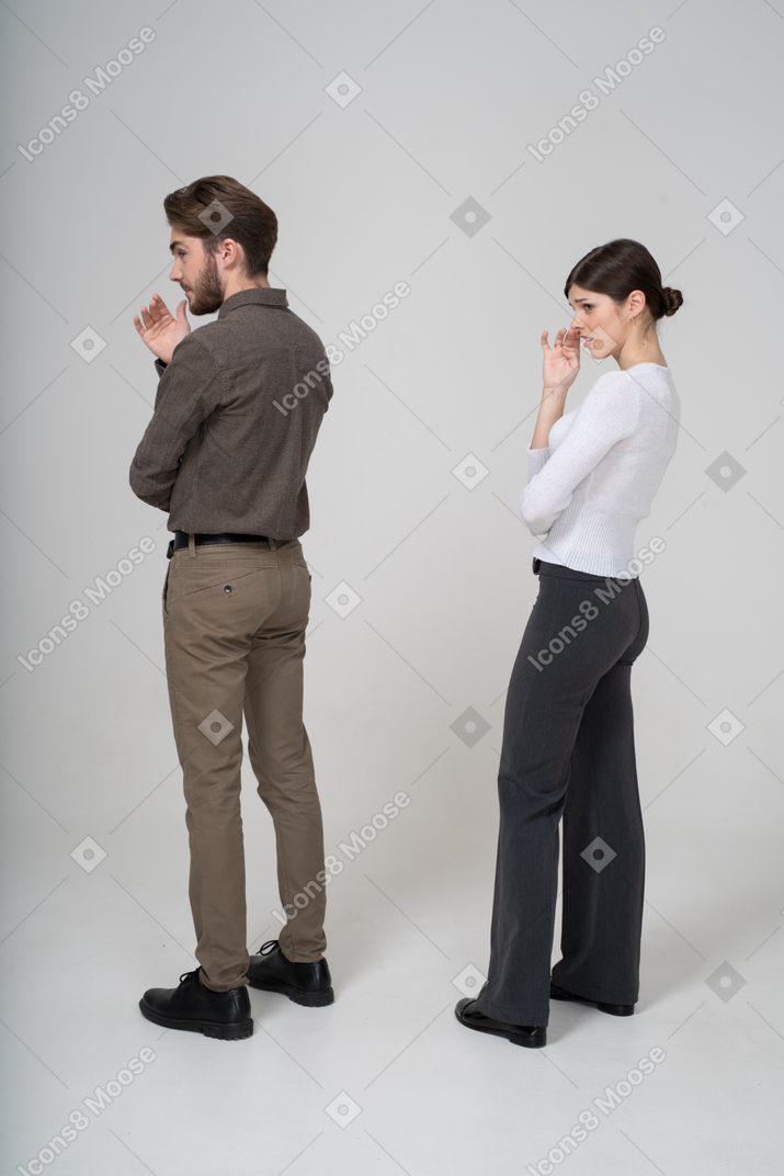 Three-quarter back view of a young couple in office clothing smelling unpleasant scent