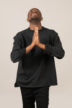 Young man looking up with praying hands