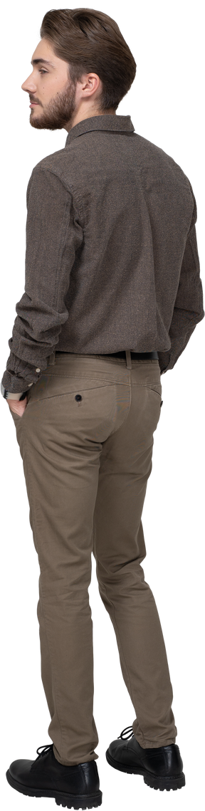 Three-quarter back view of a man in casual clothing putting hands in pocket