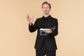 A white man in a fully black suit holding the quran