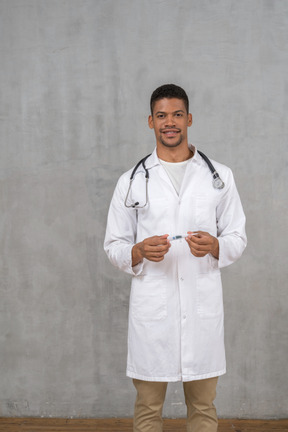 Smiling male doctor holding a thermometer