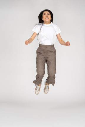 Vista frontal de una señorita saltando en calzones y camiseta doblando las rodillas
