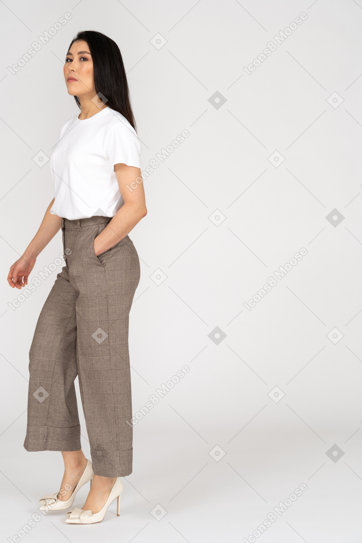 Three-quarter view of a serious young woman in breeches putting hand in pocket