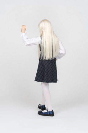 Back view of a schoolgirl raising her hand